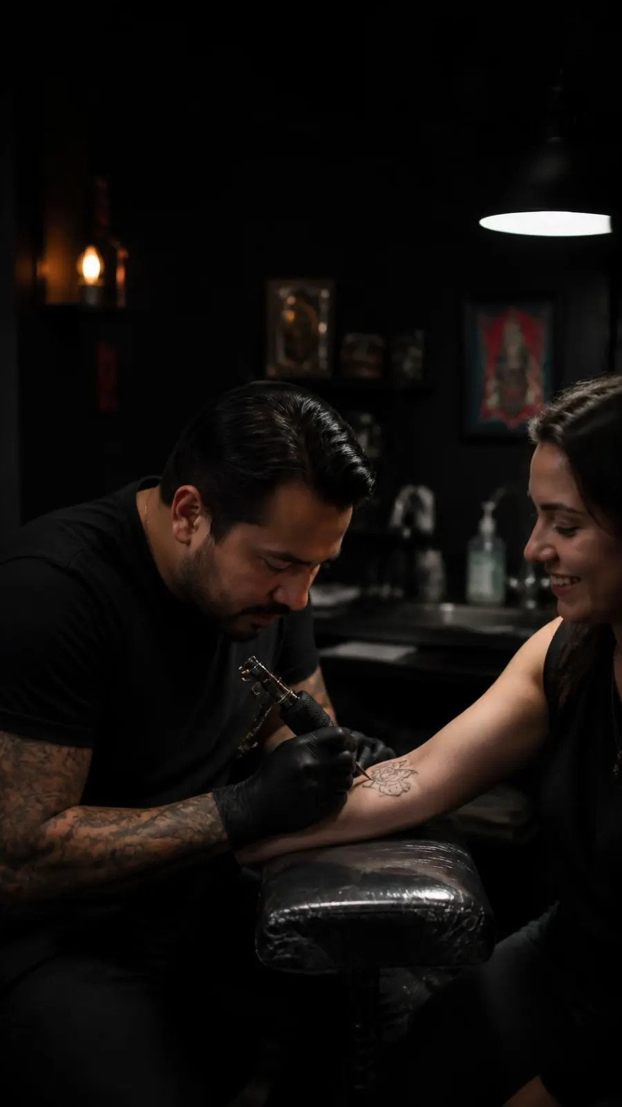 Tatuador trabajando en el antebrazo de una clienta sonriente